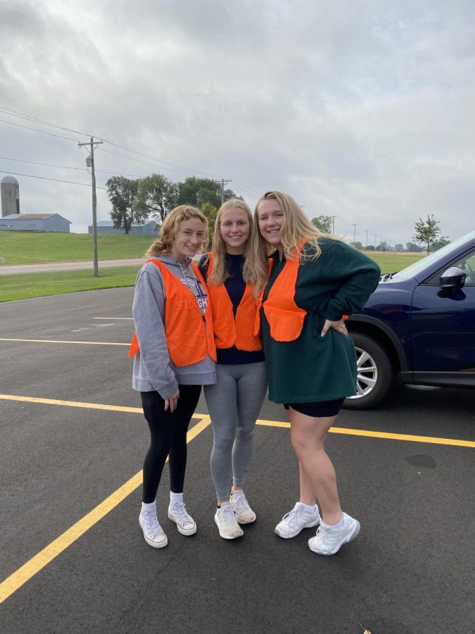 Addy McConville (left), Kortney Toso (middle), and Laci Mcphee (right) pose together in front of newly cleaned Highway B.