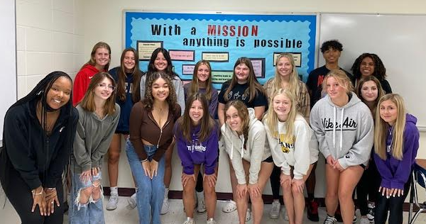 Students in the Future Educators for Literacy Class pose in front of their mission board located in room 302.