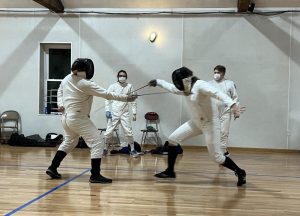 Two fencers practice during a meet.
