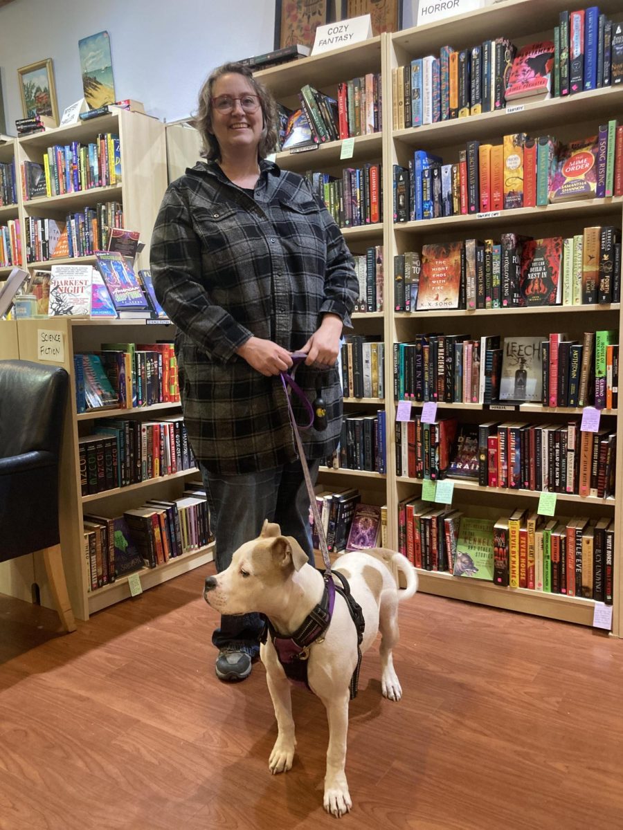 Conant stands in front of the shelves in her store, accompanied by her esteemed dog named Butterbean.